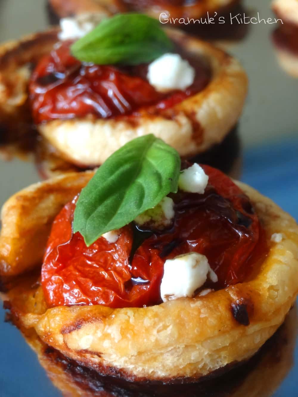 Puff pastry cherry tomato tartlets topped with basil, goat cheese and balsamic glaze.