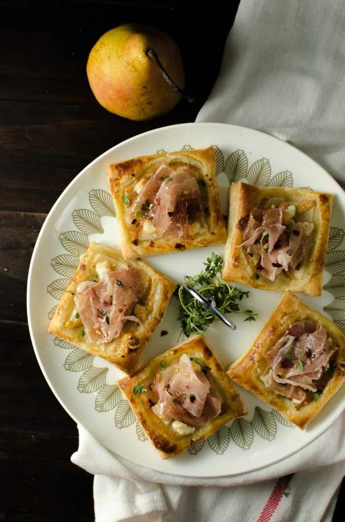 Pear, Prosciutto, Goat cheese & Honey tarts - A quick and easy appetizer idea using Puff pastry! The flavor combination of sweet Pears and tangy, creamy Goat cheese topped with salty Prosciutto and sweet Honey is going to be a definite crowd pleaser!