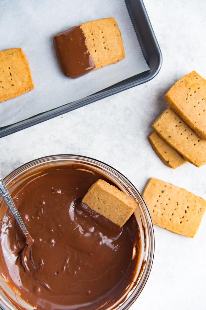 The process of half dipping espresso cookies into melted chocolate.