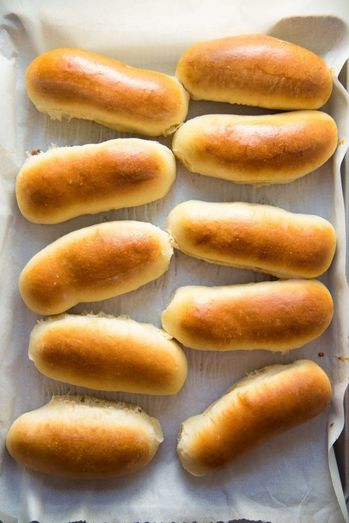 Easy Homemade Hot Dog Buns - Freshly baked hot dog buns on the baking tray with perfectly golden tops, and soft and fluffy insides.