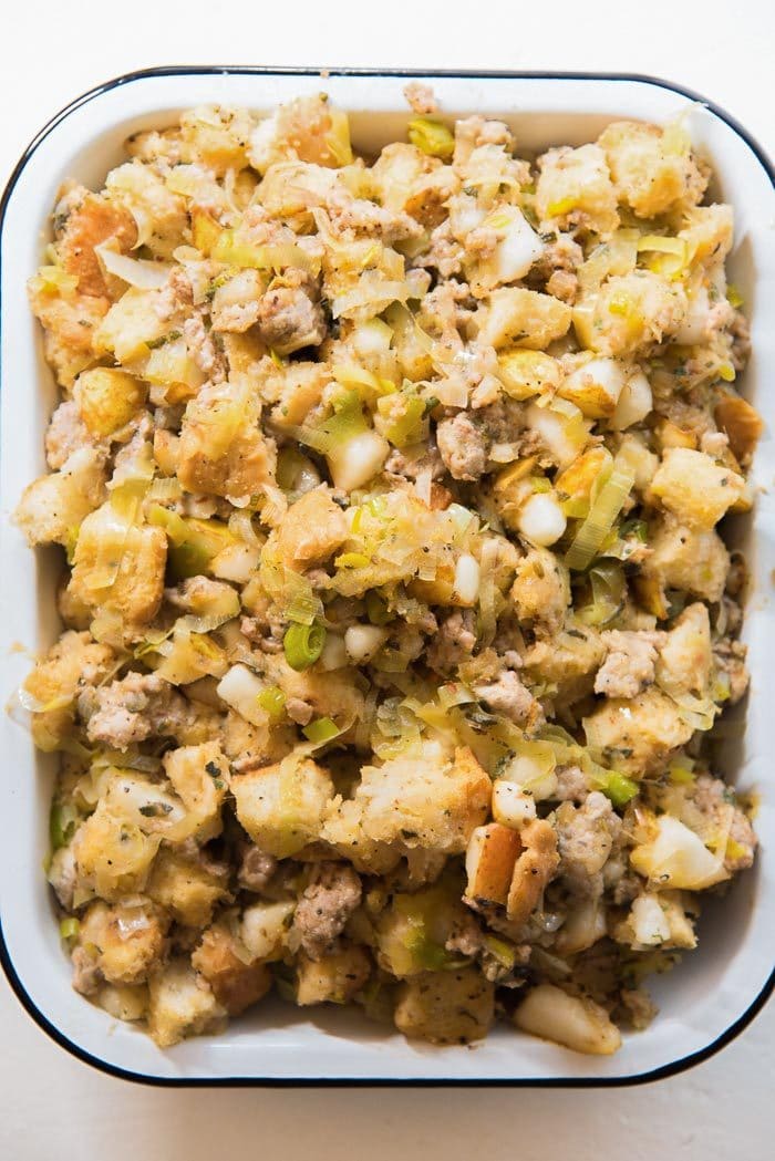 An overhead view of the sage, pear and sausage stuffing in a baking dish, ready to be cooked in the oven. 