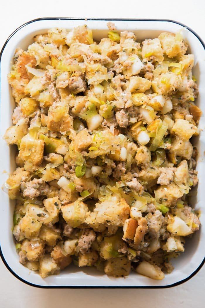 An overhead view of the sage, pear and sausage stuffing in a baking dish, ready to be cooked in the oven. 