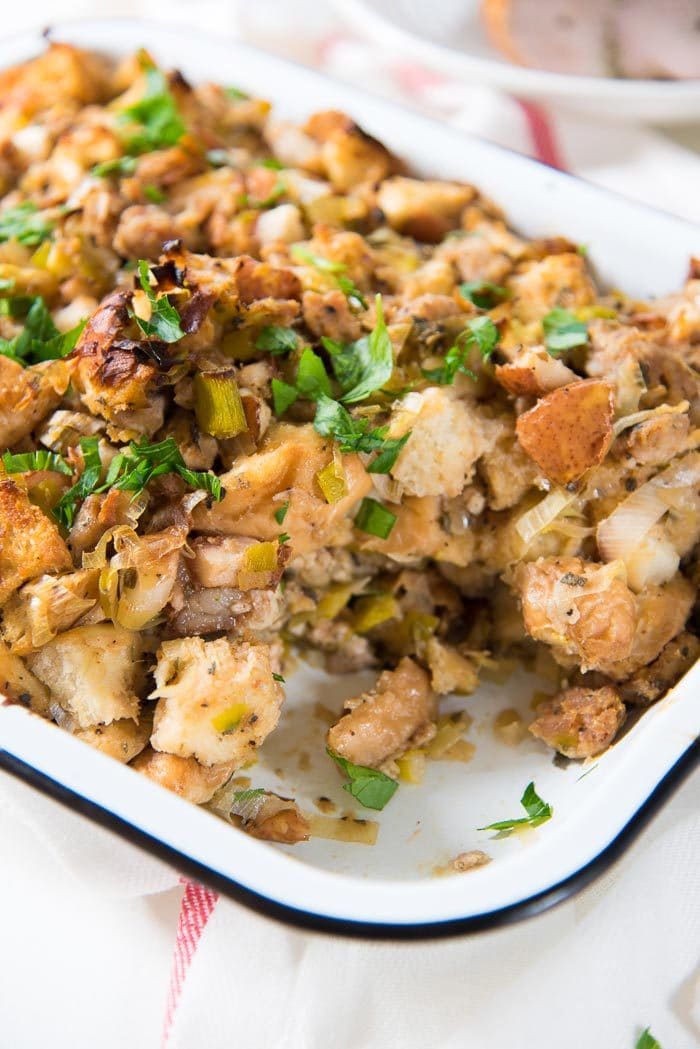 Sage Pear Sausage Stuffing in a white enamel baking dish, with the corner piece taken out. 