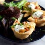 Mini tuna quiches with salad leaves on a small black platter.