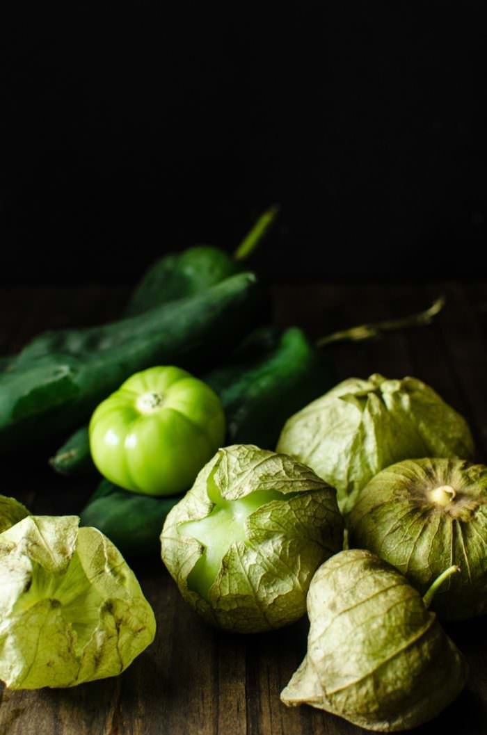 Fresh tomatillos and poblano peppers on a table