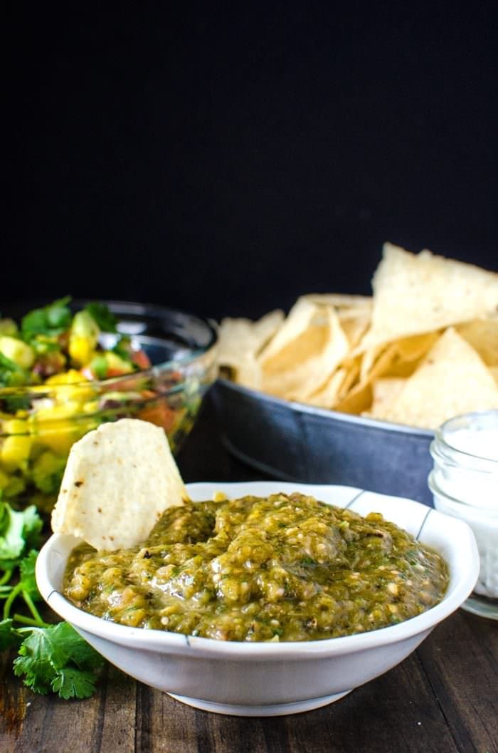 Spicy salsa verde with a corn chip in a bowl