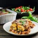 Two manicotti pasta shells stuffed with ground beef and ricotta and spinach filling on a white plate.