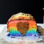 Rainbow ice cream cake cut in half to show rainbow colors and heart shape in the middle.
