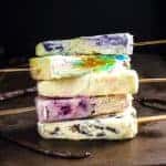 Stack of creamy vanilla popsicles with different colors and fruity fillings.