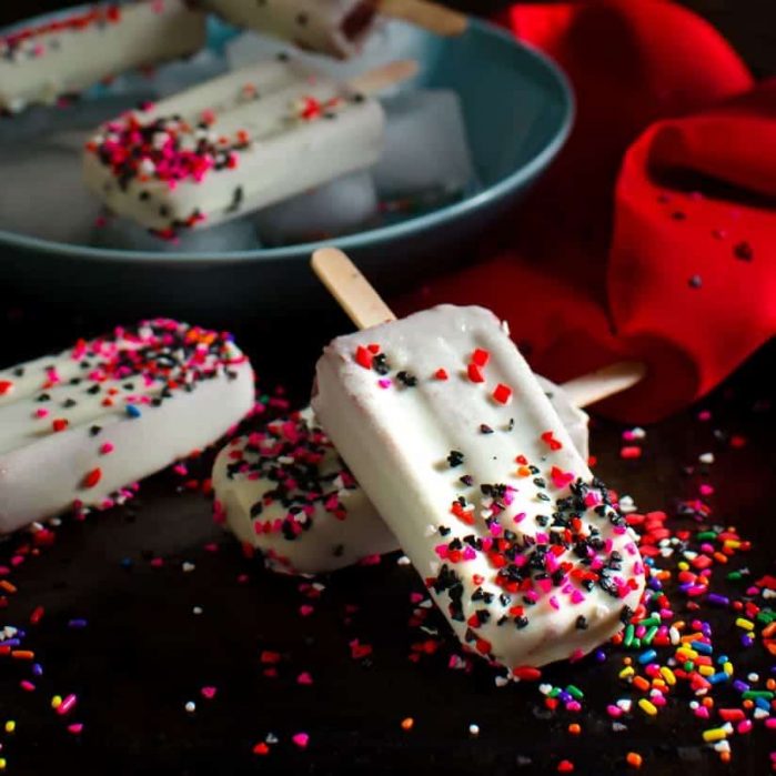 Red Velvet Pudding Popsicles - These tangy, creamy, white chocolate magic shell covered,  Buttermilk Chocolate Pudding Popsicles, are simple to make, insanely delicious, and pretty inside and out. Just like the crazy, lovable Harley Quinn!