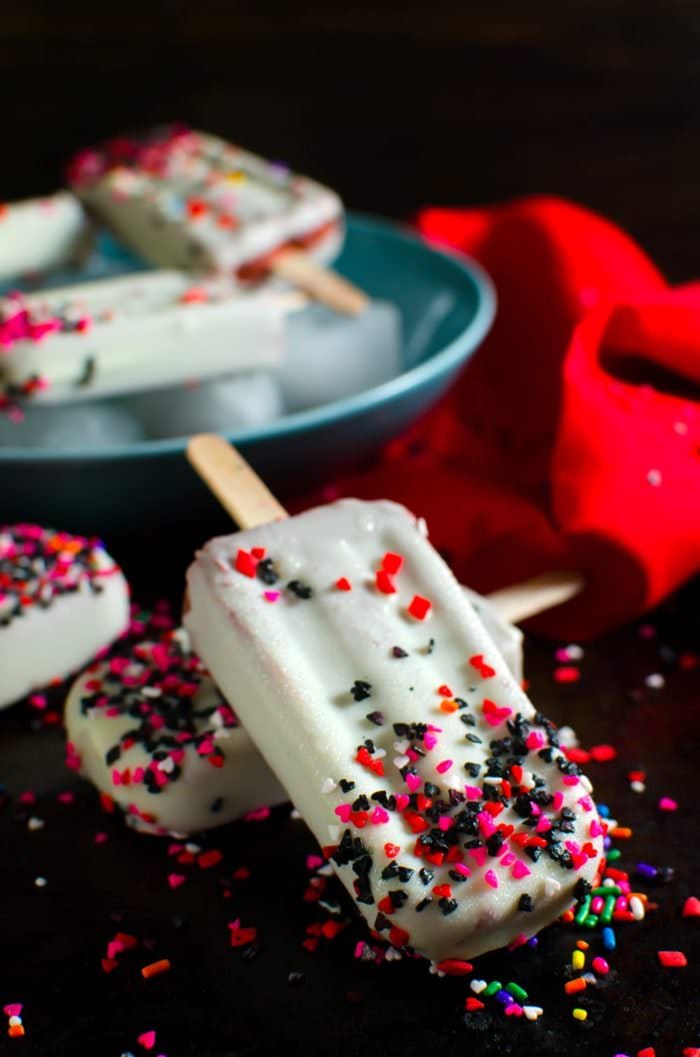 Red Velvet Pudding Popsicles - These tangy, creamy, white chocolate magic shell covered,  Buttermilk Chocolate Pudding Popsicles, are simple to make, insanely delicious, and pretty inside and out. Just like the crazy, lovable Harley Quinn!
