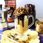 Coffee affogato sundae in a big glass cup, topped with chocolate fudge sauce and coffee streusel.