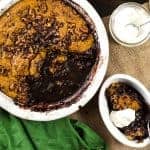 Overhead image of a pumpkin self saucing pudding with chocolate sauce in a big baking dish.