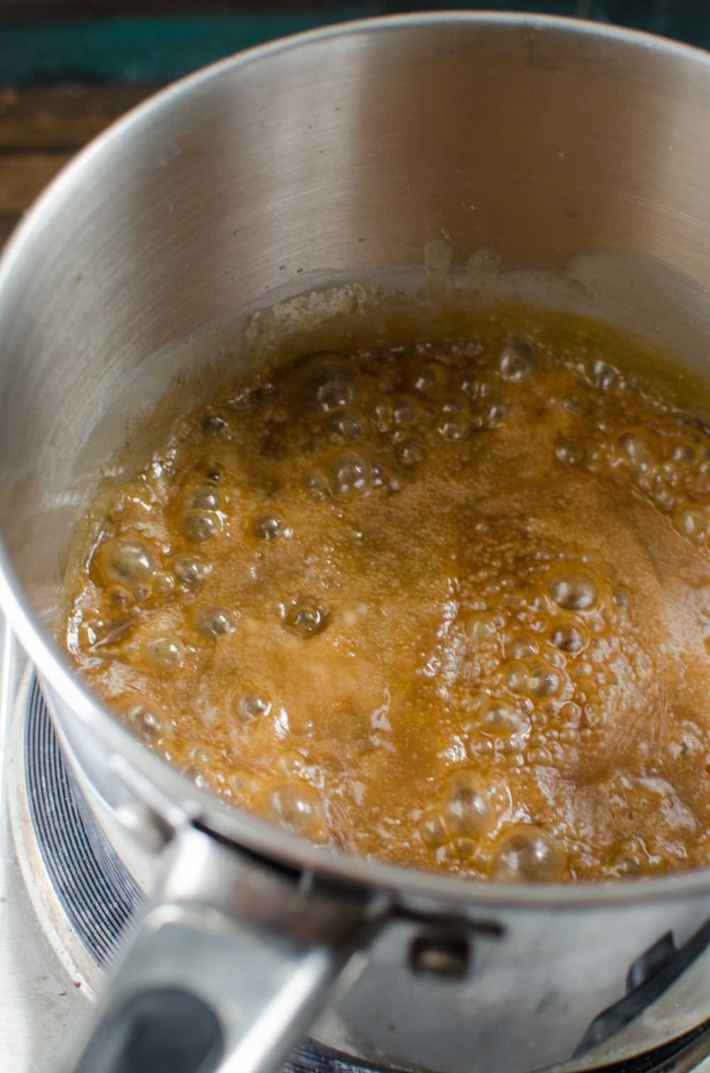 Heating brown sugar in a big stainless steel saucepan.