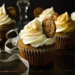 A gingerbread cupcake with swirled cream cheese frosting and a gingersnap cookie on top.