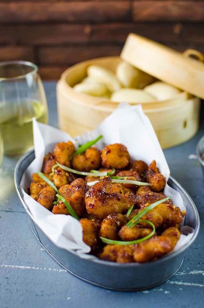 Deliciously easy, Spicy Asian Popcorn Shrimp Bao - Perfect for busy weeknights. Restaurant-quality, flavor-packed meal in just 15 - 20 minutes with crispy oven-baked popcorn shrimp, tossed in a spicy Asian sauce and then served with steamed Chinese bao buns (or slider buns) with crunchy carrots and spring onions!  