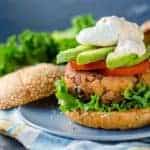 Crispy tuna burger with tomato, avocado and a poached egg on a plate.