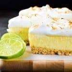 Frozen margarita pie with pretzel crust and meringue topping on a wooden board.