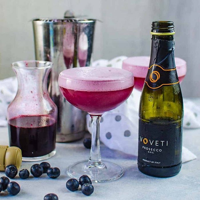 Sparkling Blueberry elderflower sour - This prosecco cocktail is a cross between a mimosa, and a whiskey sour. A gorgeous fruity and floral bubbly cocktail that is perfect for celebrations!