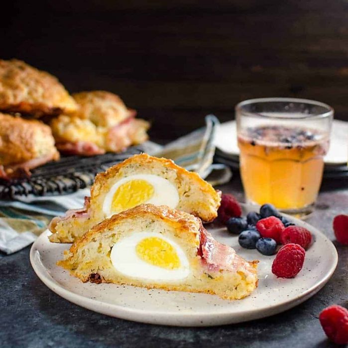 Bacon wrapped Egg Stuffed Breakfast Biscuits (Breakfast Scones) - Cheesy and herby buttermilk biscuits that are delightfully soft in the middle and extra flaky on the outside, and stuffed with a perfectly cooked egg and wrapped with bacon for good measure. Perfect for Brunch. 