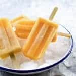 Stack of lychee cantaloupe popsicles on crushed ice in a white plate.
