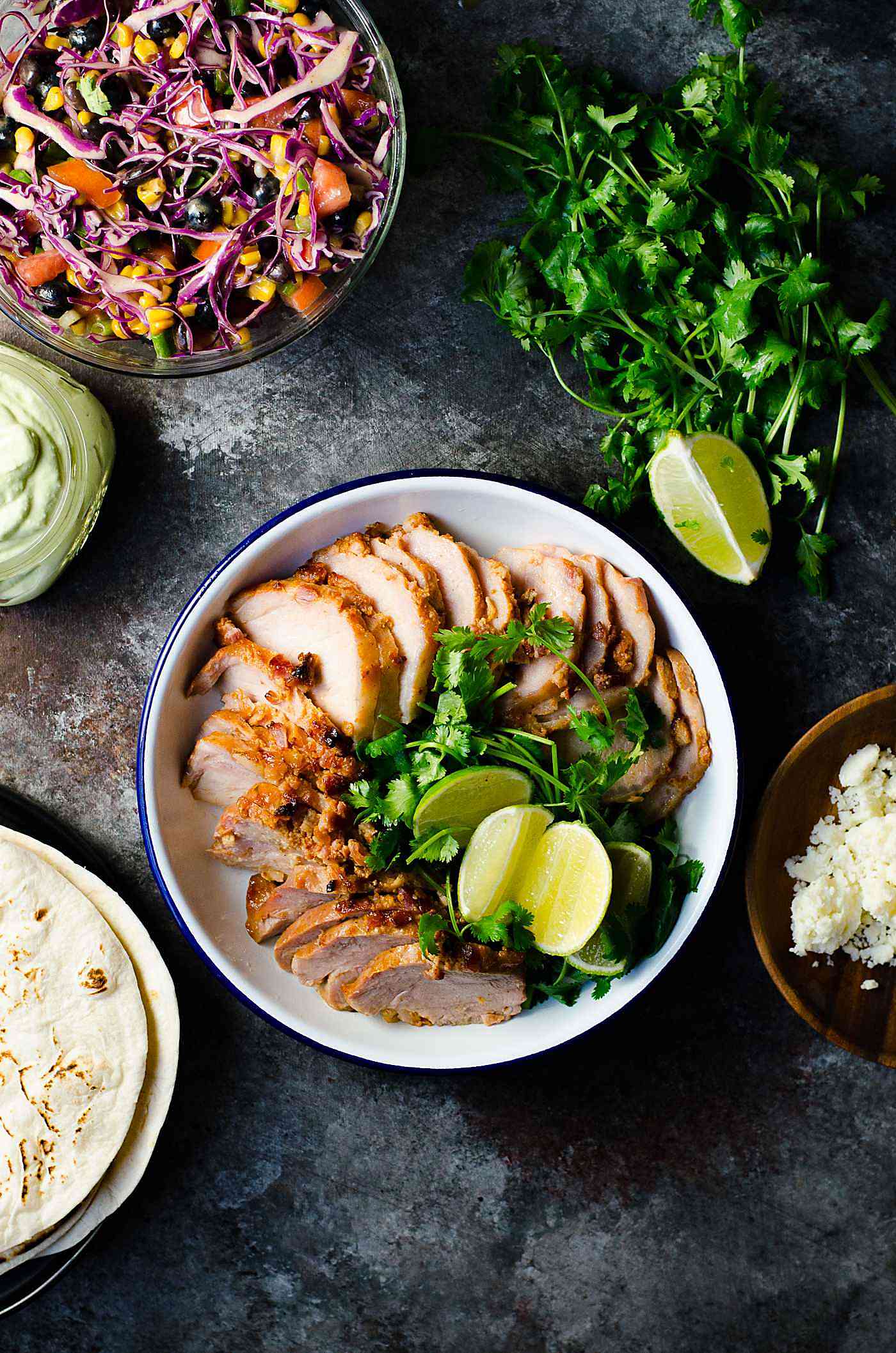 Roasted Pork Tacos  with blueberry coleslaw - Tacos with tender pieces of roasted applewood smoked bacon Pork loin, and topped witha a fresh and light blueberry rainbow coleslaw with an almond honey mustard dressing (no mayonnaise), and an Jalapeno avocado crema. A meal that's ready in 30 minutes with some life saving shortcuts!