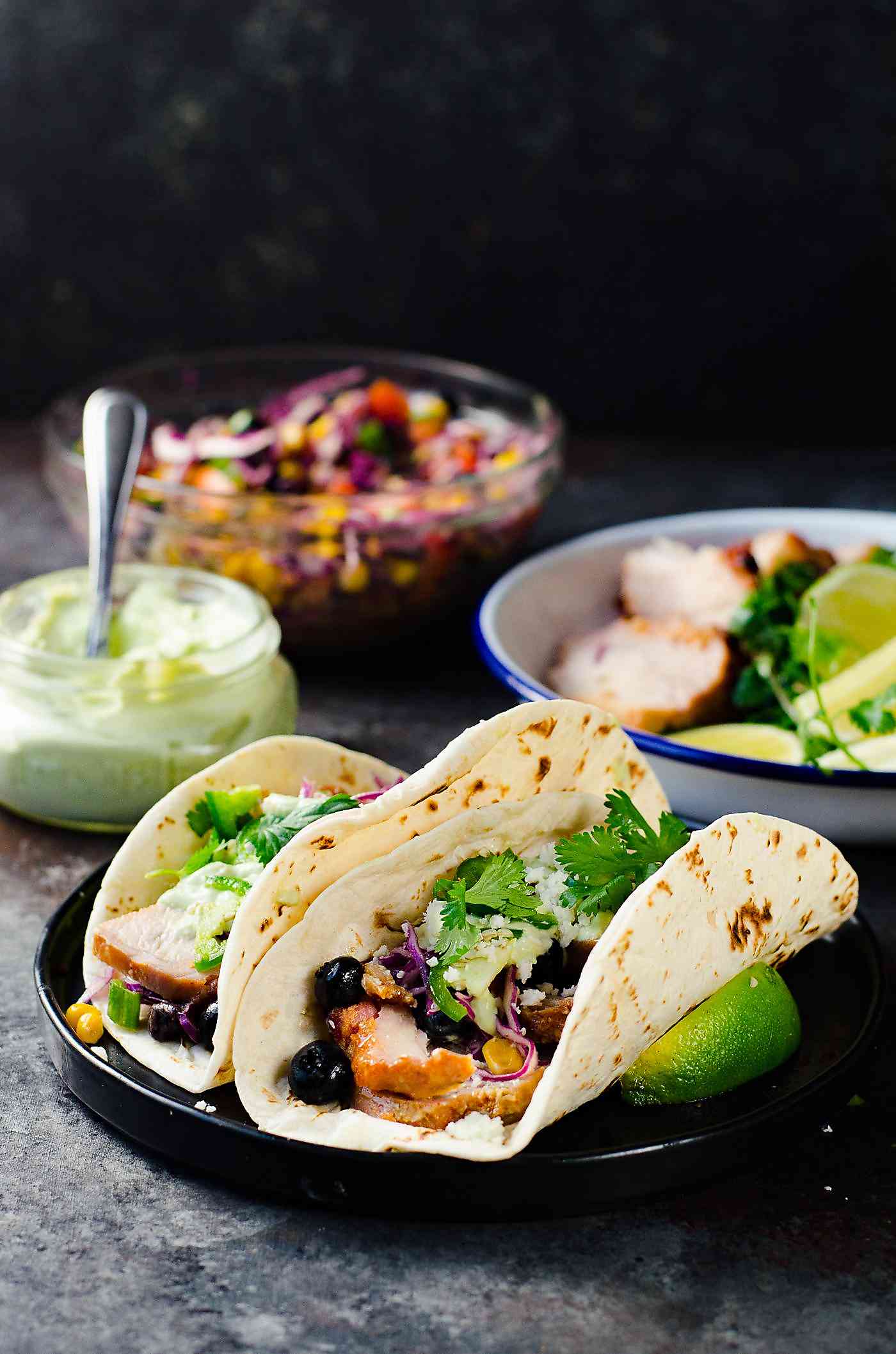 Roasted Pork Tacos  with blueberry coleslaw - Tacos with tender pieces of roasted applewood smoked bacon Pork loin, and topped witha a fresh and light blueberry rainbow coleslaw with an almond honey mustard dressing (no mayonnaise), and an Jalapeno avocado crema. A meal that's ready in 30 minutes with some life saving shortcuts!