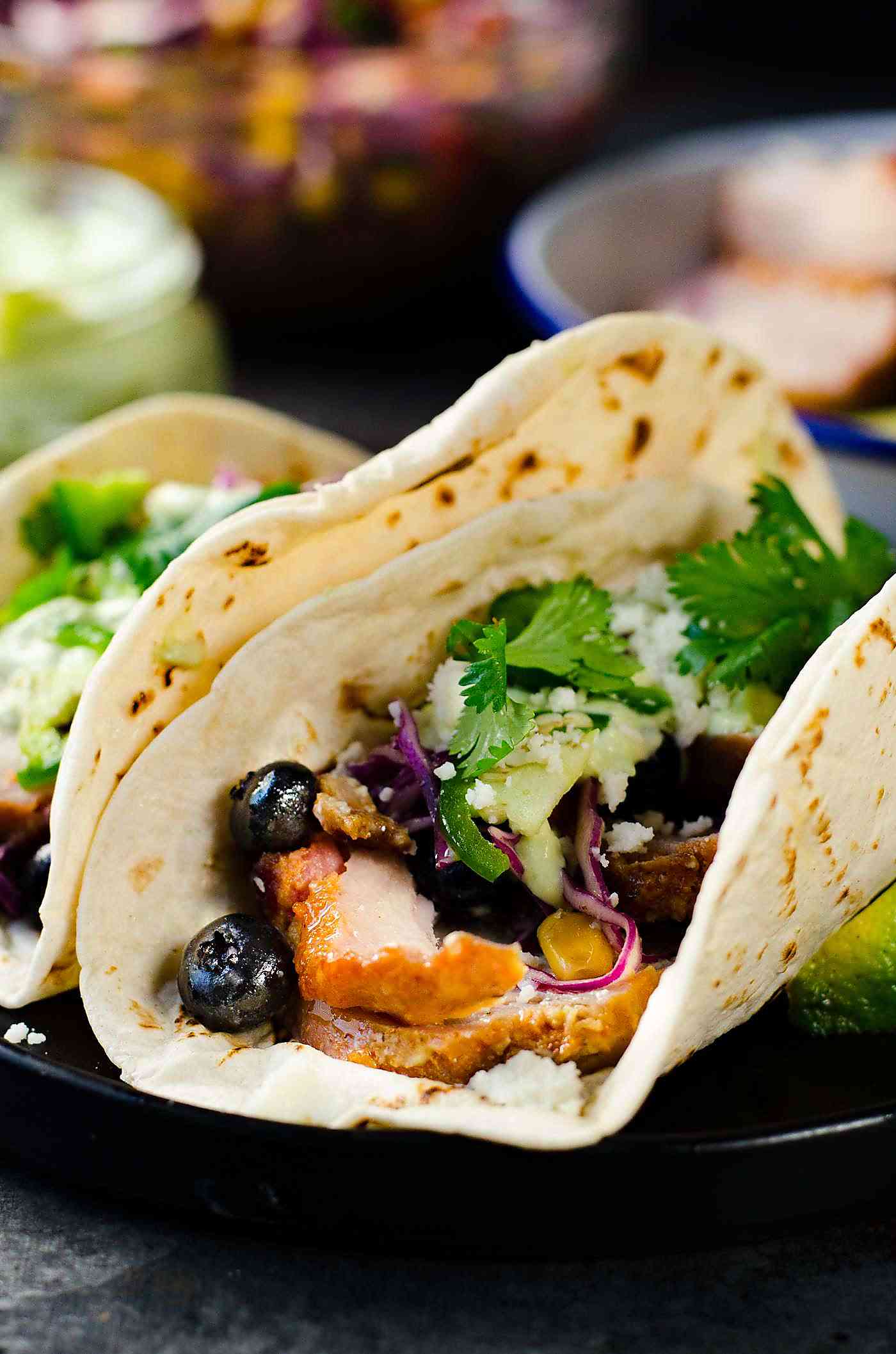 Roasted Pork Tacos  with blueberry coleslaw - Tacos with tender pieces of roasted applewood smoked bacon Pork loin, and topped witha a fresh and light blueberry rainbow coleslaw with an almond honey mustard dressing (no mayonnaise), and an Jalapeno avocado crema. A meal that's ready in 30 minutes with some life saving shortcuts!