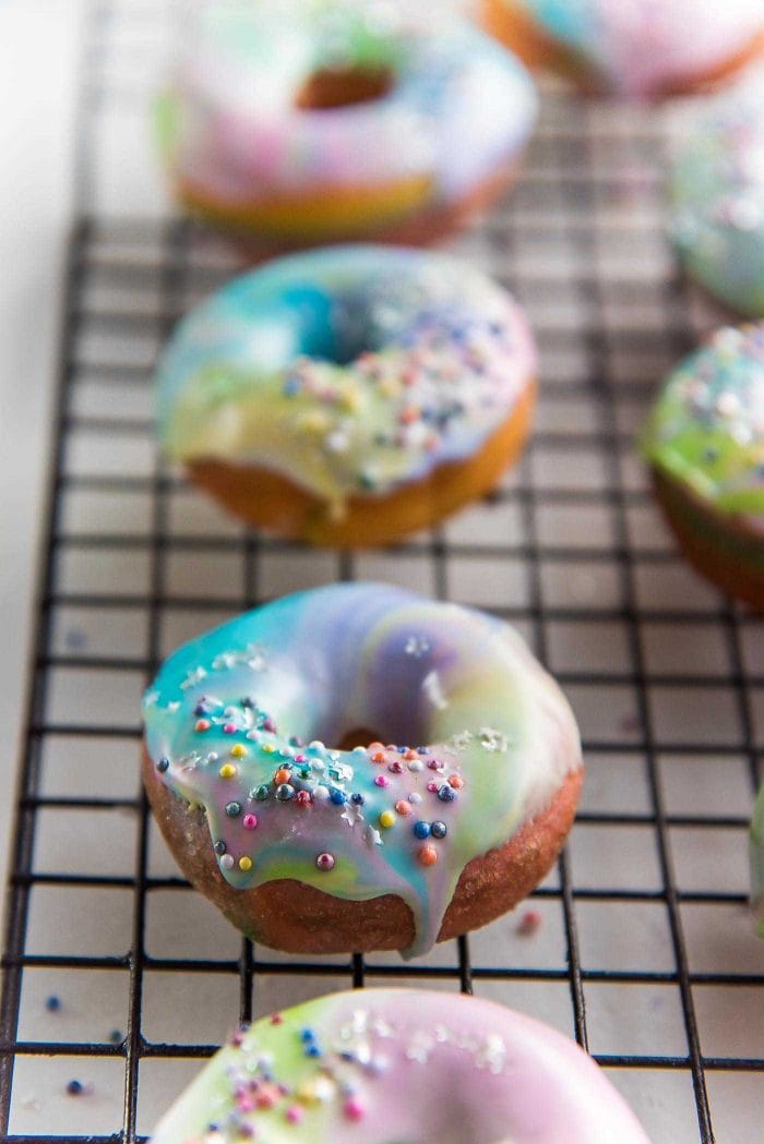 Mini Rainbow Donuts with a unicorn Glaze- Colorful and gorgeousfried donuts made with rainbow colored dough and coated with a rippled unicorn glaze. 