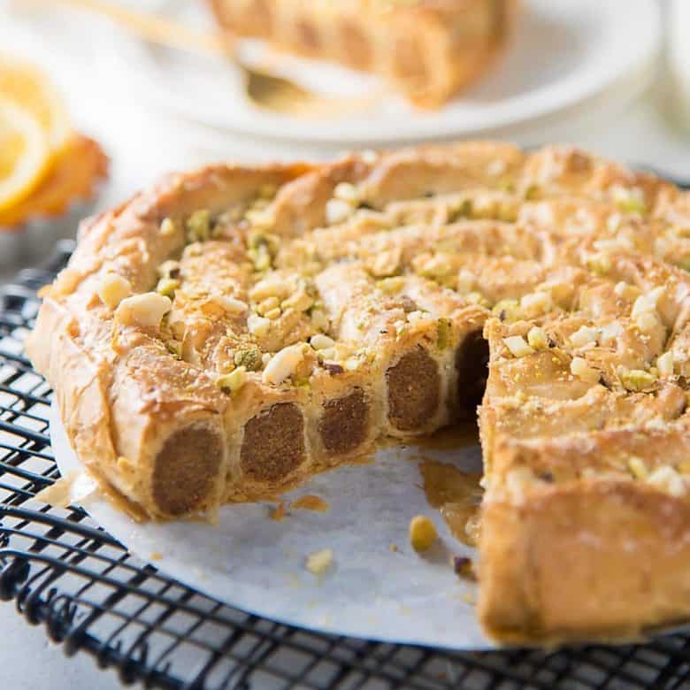 Almond m'hancha on a wire rack with a slice taken out to show almond paste filling inside the coiled pastry. 