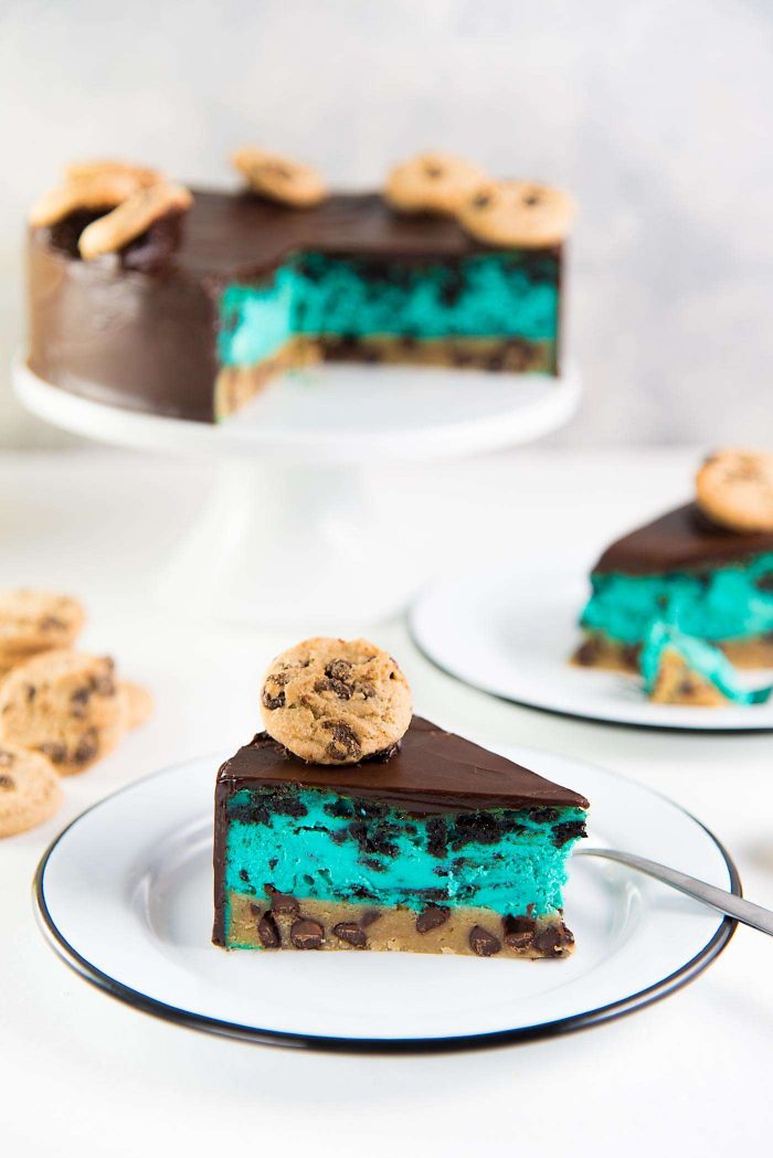 Cookie Monster Cheesecake - A fudgy chewy chocolate chip cookie blondie, topped with a creamy cookie and cream cheesecake loaded with Oreos and coated with a layer of chocolate ganache. Perfect dessert for cookie lovers. From the Secret Layer Cakes cookbook.