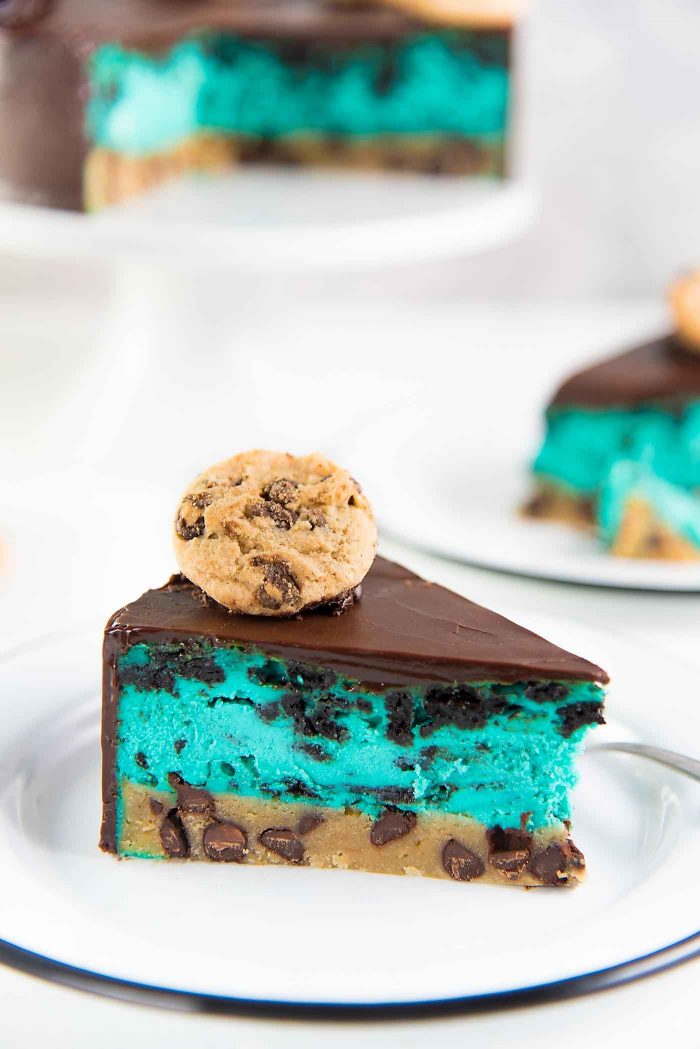Cookie Monster Cheesecake - A fudgy chewy chocolate chip cookie blondie, topped with a creamy cookie and cream cheesecake loaded with Oreos and coated with a layer of chocolate ganache. Perfect dessert for cookie lovers. From the Secret Layer Cakes cookbook.