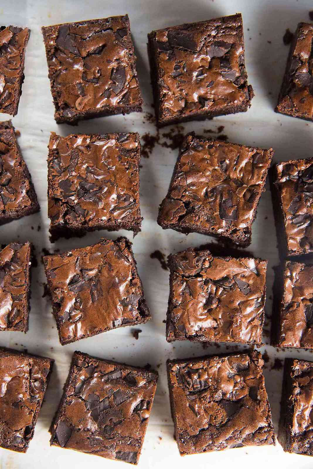 An overhead view of fudgy cocoa brownies cut into squares with a glossy crackly surface. 