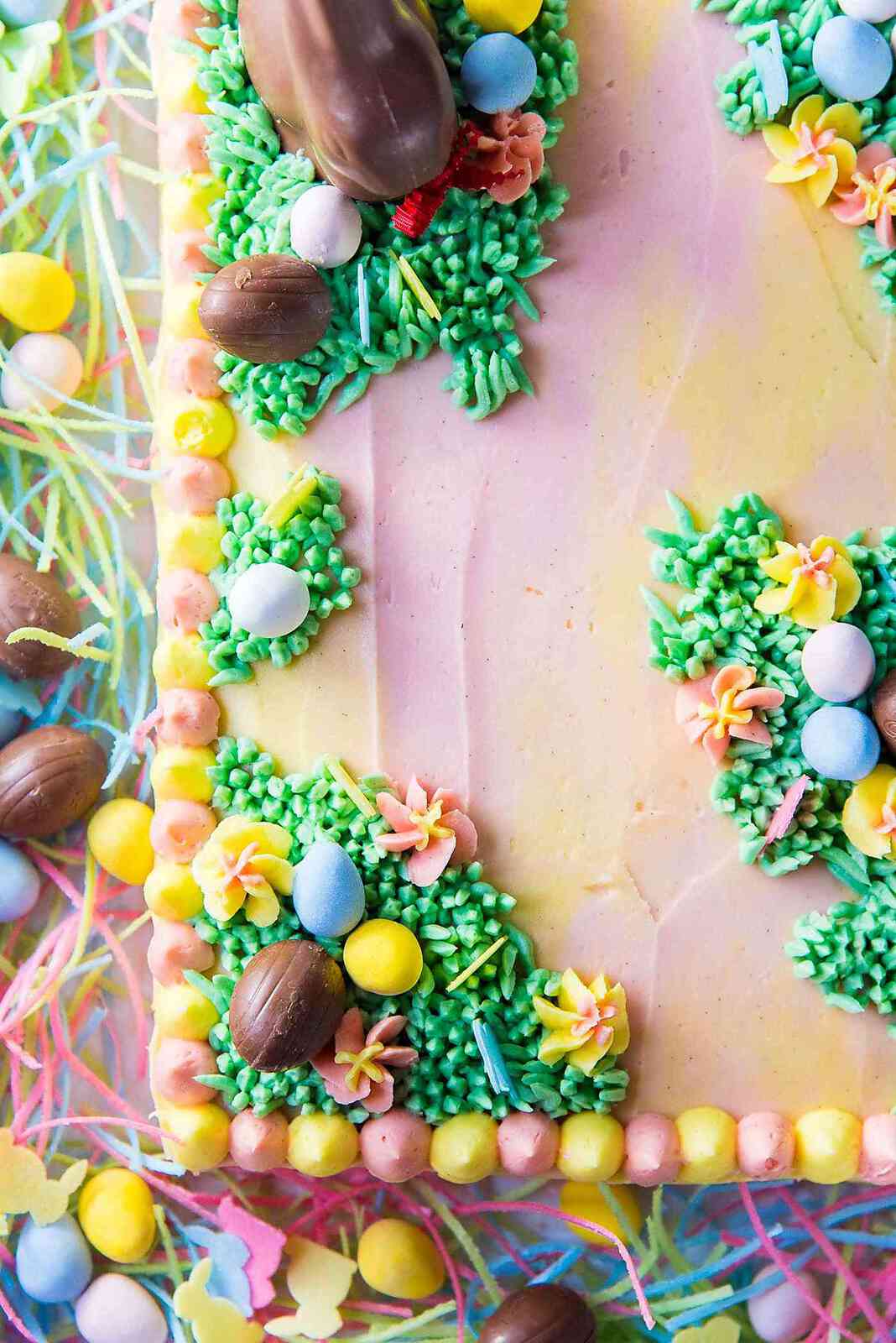 Pastel Easter Cake - A swirled pastel cake with pastel buttercream, decorated with patches of buttercream grass, buttercream flowers, and chocolate Easter eggs.