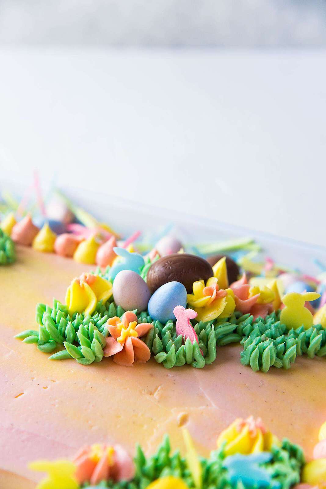 Pastel Easter Cake - Create a spring and Easter theme with grass, flowers and bunnies on the surface of the cake.