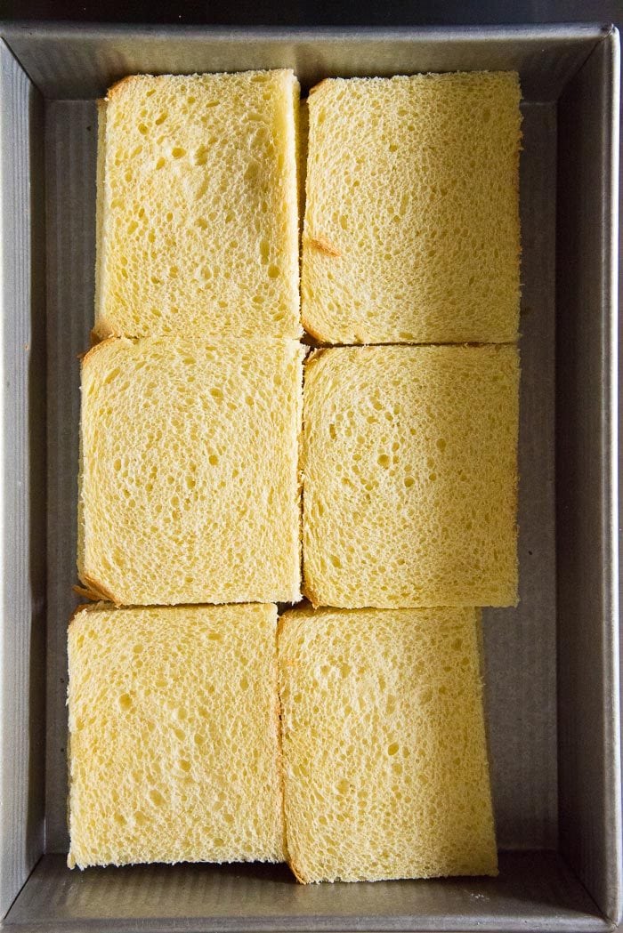 6 slices of brioche bread placed in a buttered dish, with the edges trimmed.