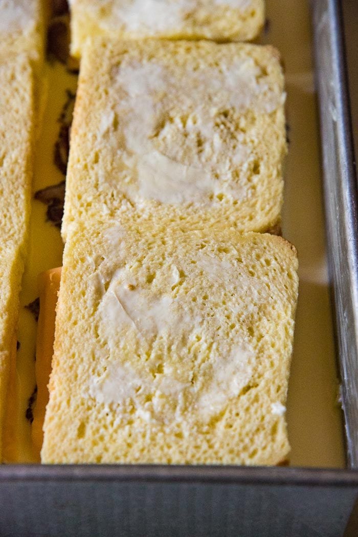 A close up of 2 sandwiches, in a dish with the top buttered.