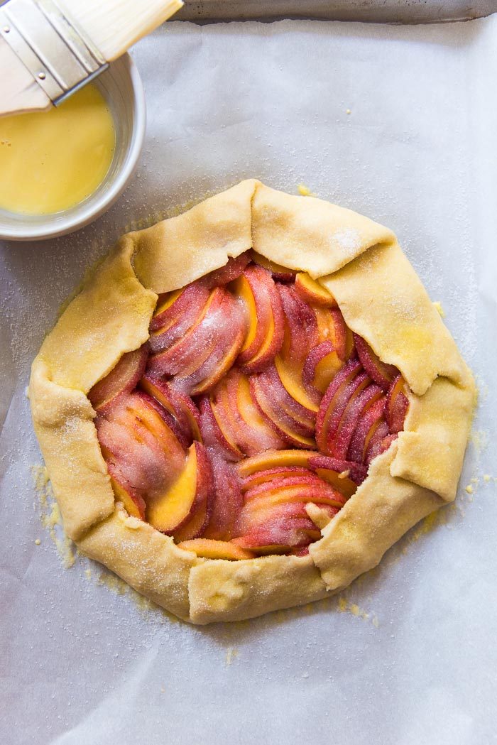 Fold over the edges of the pie crust, as a freeform peach galette. Brush the edges with an egg wash before baking.