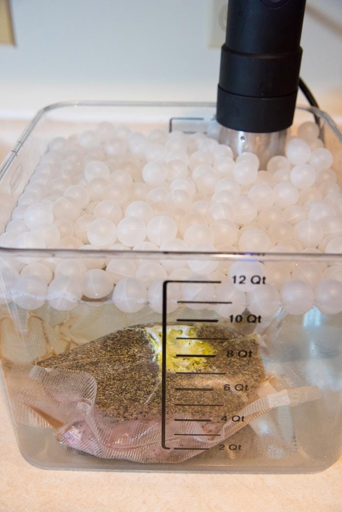 A 12 qt tub filled with water, with the vacuum packed rump roast submerged in it, and the sous-vide cooker attached to the tub.