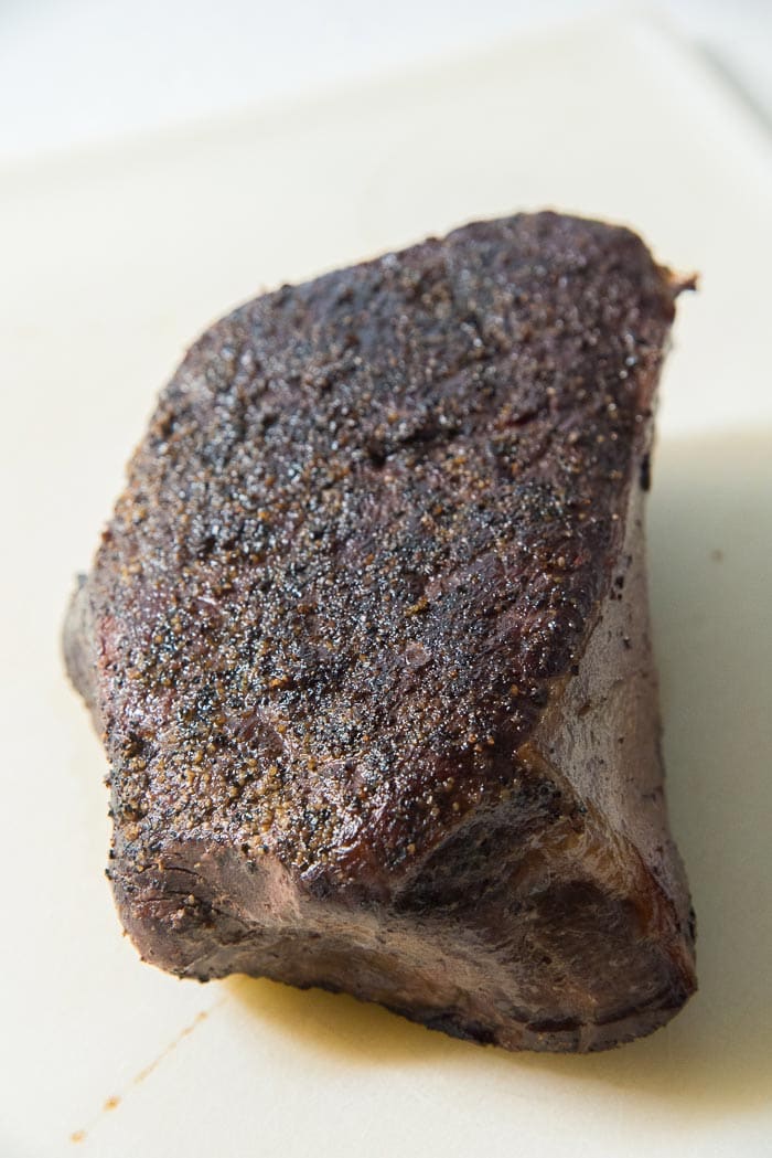 Sous-vide cooked rump roast with a caramelized crust on a white cutting board.