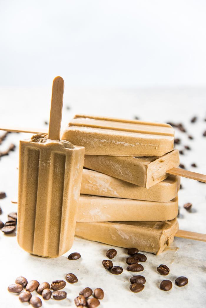 A stack of iced coffee coconut milk popsicles on a grey table top.