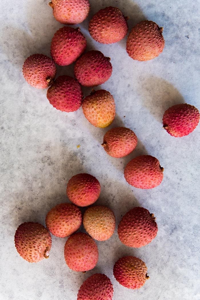 An overhead image of Fresh lychee still in their bright red skin.