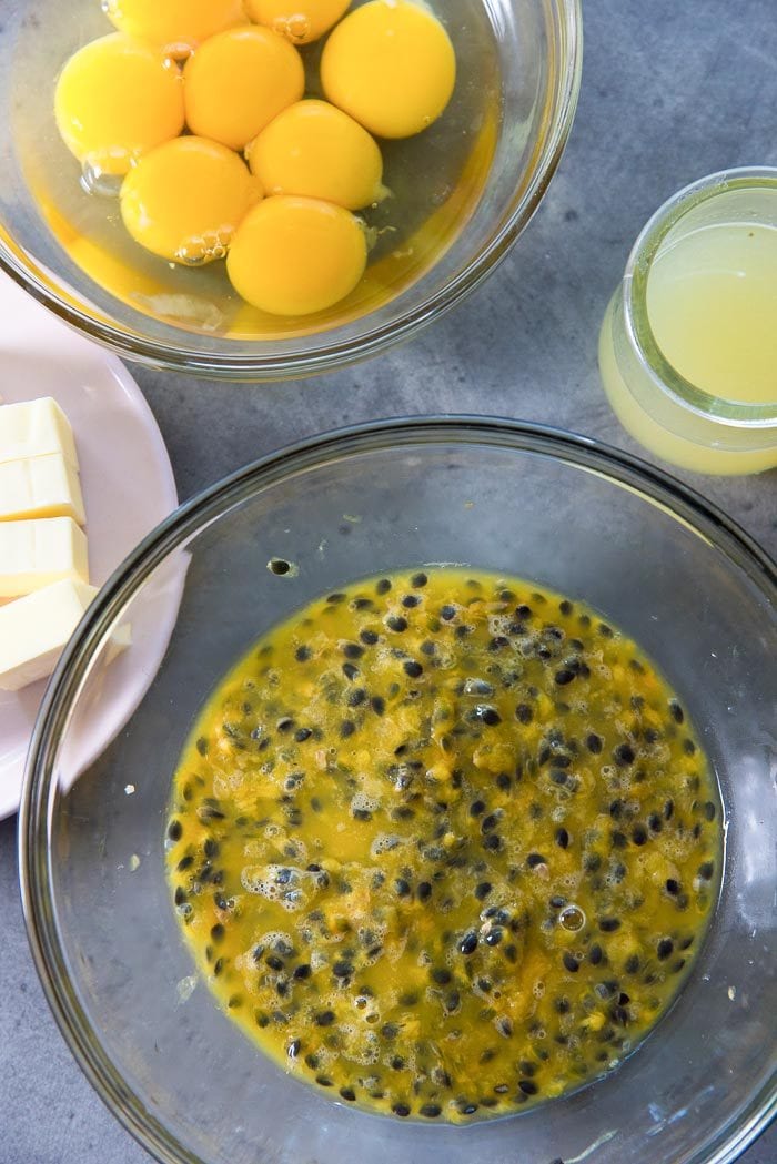 Ingredients for Passion Fruit curd on a grey table. From fresh Passion fruit pulp, unsalted butter, lemon juice, egg yolks. 