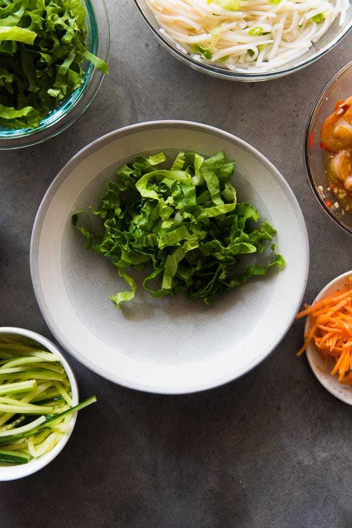 Assembling Garlic Lime Shrimp Rice noodle salad. Add the shredded lettuce first.