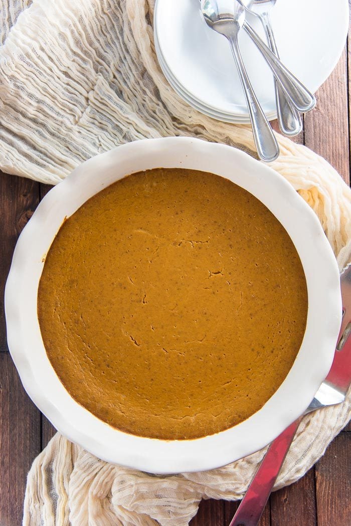 A baked crustless pumpkin pie in a white pie dish. Gluten free and refined sugar free, easy and fool proof.