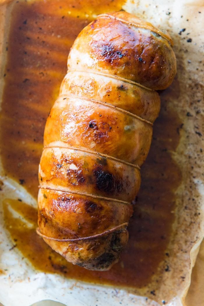 A slow roasted turkey roulade straight out of the oven, on a baking tray, with pan dripping.