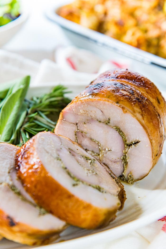 A close up with the slow roasted turkey roulade with caramelized skin, cut into thick slices.