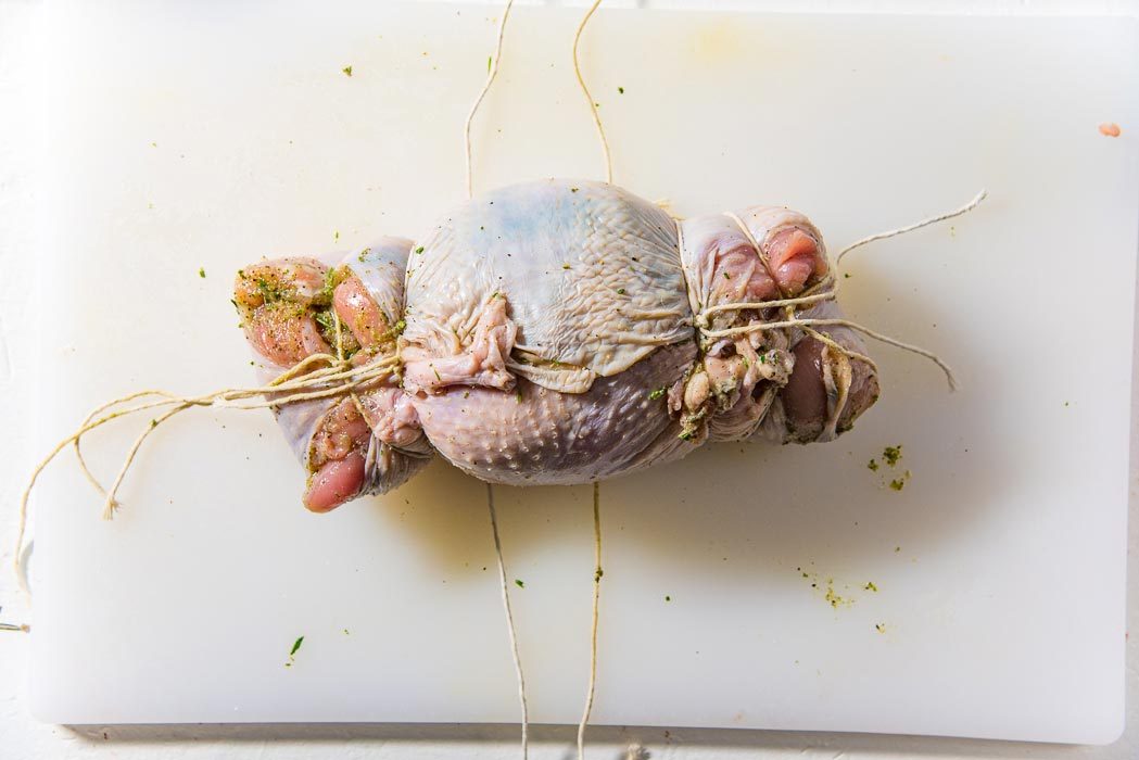 Tie up the turkey roulade with cotton twine, starting from the edges and working towards the middle.