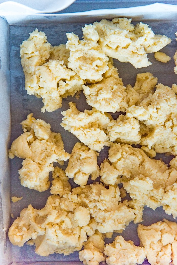 Mixed, soft and sticky shortbread crust, dolloped into the prepared parchment lined pan. 