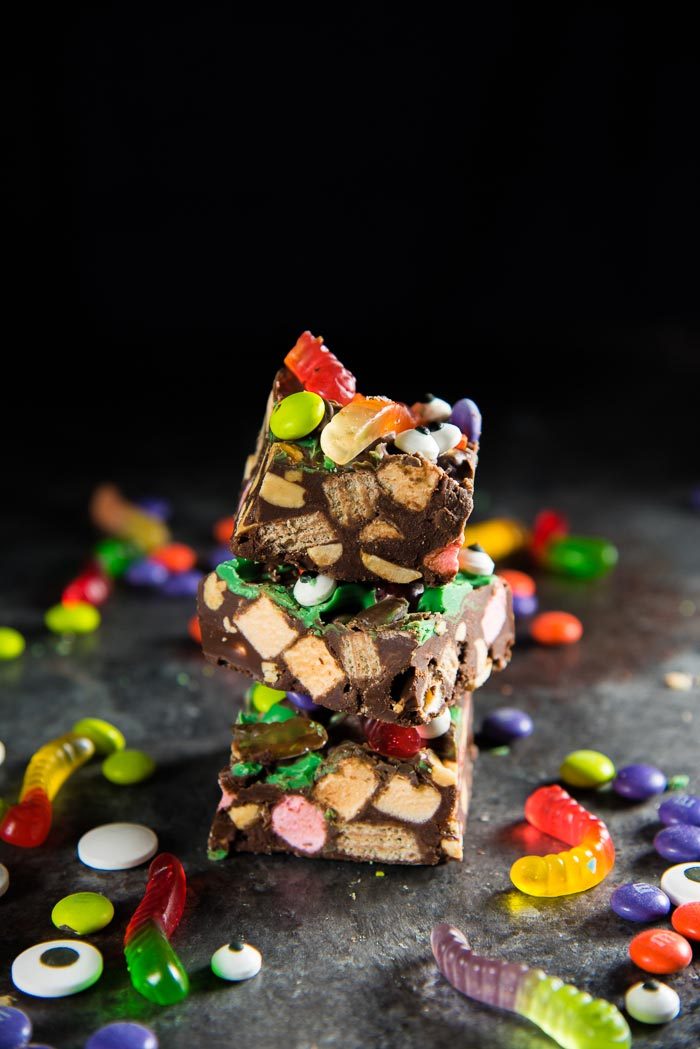 A stack of Halloween rocky road slices, next to halloween candy on a table top.